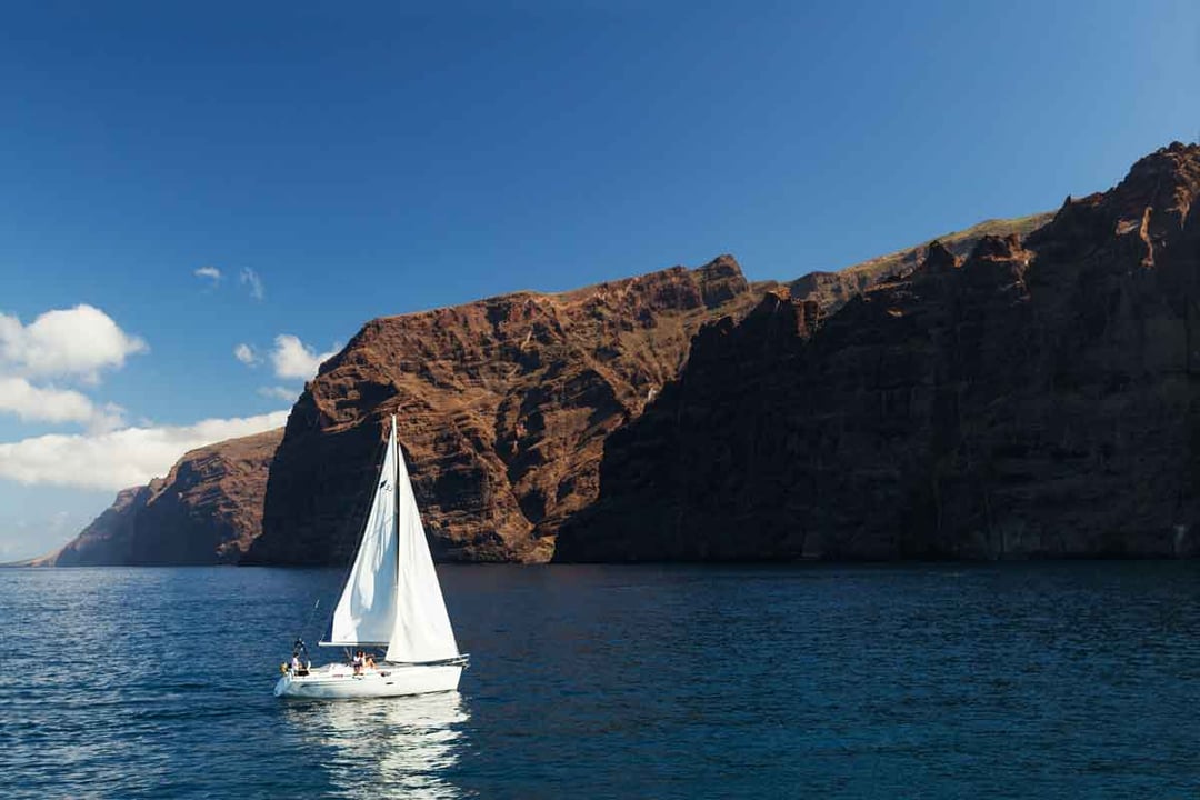 A yacht sailing past the Los Gigantes cliffs in Tenerife