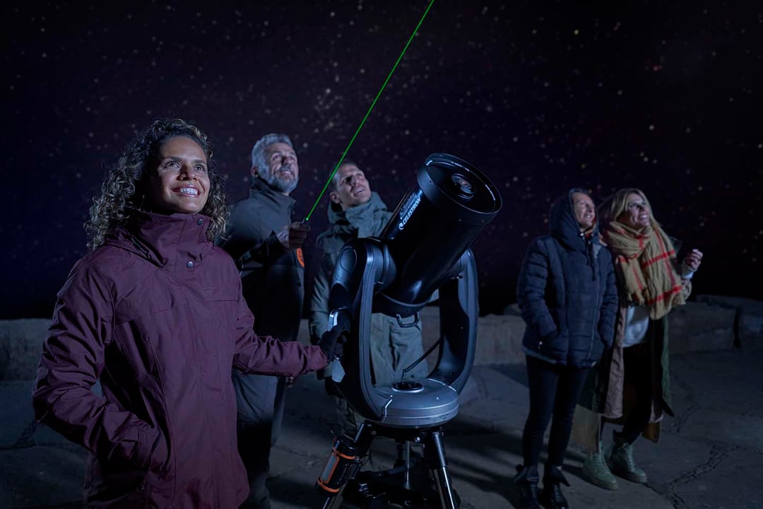 Eine Gruppe von fünf Personen, die vom Teide auf Teneriffa aus mit einem Teleskop die Sterne beobachten.