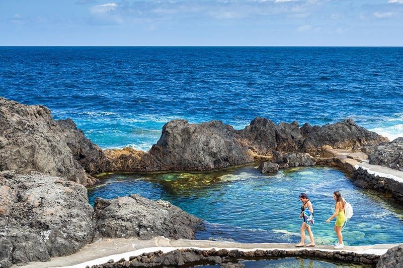 Twee toeristen badend in de natuurlijke baden van Garachico op Tenerife